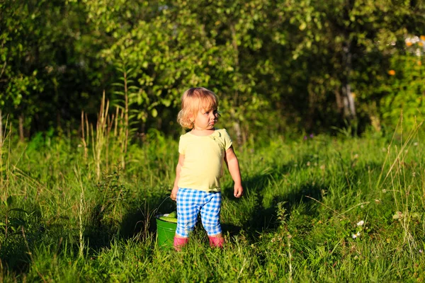 Meisje oogsten komkommers in tuin — Stockfoto