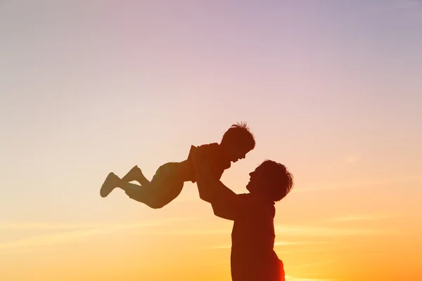 Pappa och lilla son silhuetter spela vid solnedgången — Stockfoto