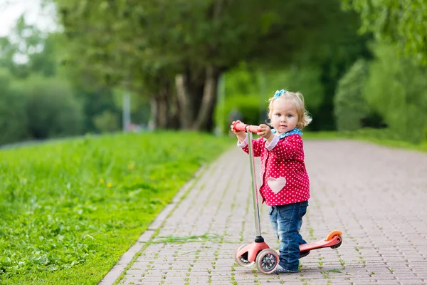 Niedliches kleines Mädchen, das im Sommer Roller fährt — Stockfoto