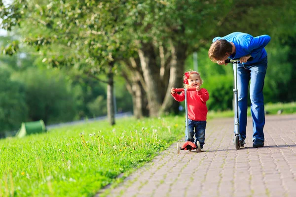 Vader en kleine dochter rijden scooters — Stockfoto