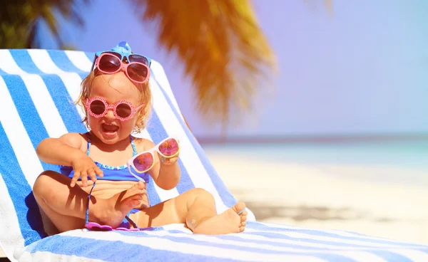 Cute dziewczynka próbuje na okulary przeciwsłoneczne na plaży — Zdjęcie stockowe