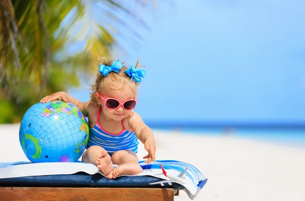 Little girl with globe and toy plane on beach — Stock Photo, Image