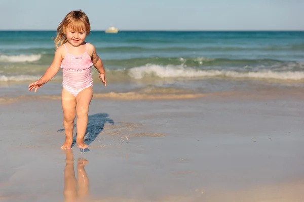 Niedliche kleine Mädchen spielen mit Wasser am Strand — Stockfoto