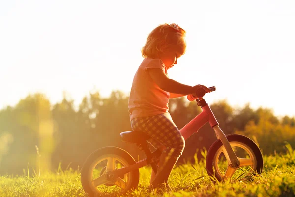 Bambina in sella alla bici al tramonto, bambini attivi — Foto Stock