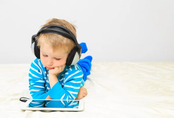 Mały chłopiec z słuchawki za pomocą panelu dotykowego — Zdjęcie stockowe