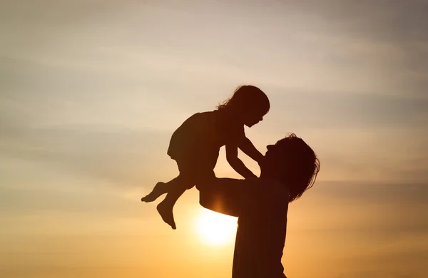 Pai e pequena filha silhuetas ao pôr do sol — Fotografia de Stock