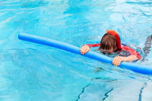 Niño aprende a nadar con fideos de la piscina — Foto de Stock