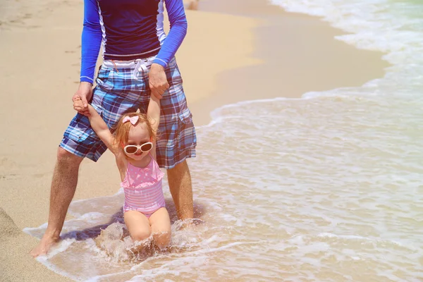 Vader en dochtertje spelen met golven op het strand — Stockfoto