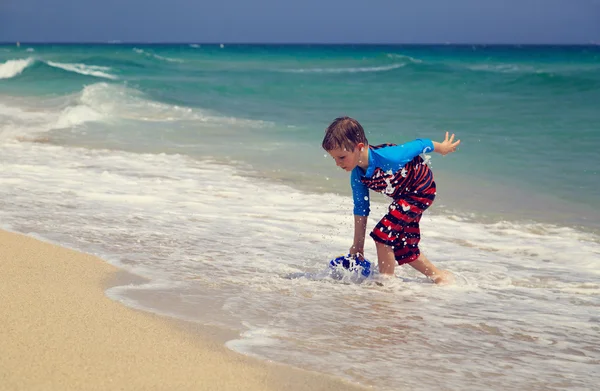 Kleine jongen spelen met water op tropisch strand — Stockfoto