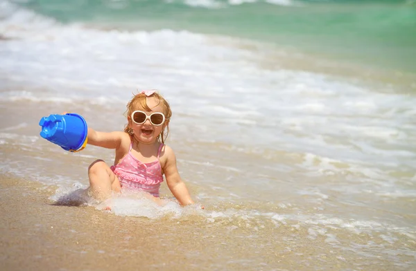 Милая маленькая девочка играет с водой на пляже — стоковое фото