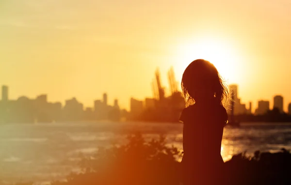 Liten flicka tittar på sunset city — Stockfoto