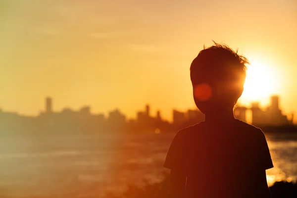 Liten pojke tittar på sunset city — Stockfoto