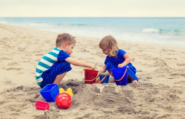 Çocuklar yaz plajında kumla oynarlar.