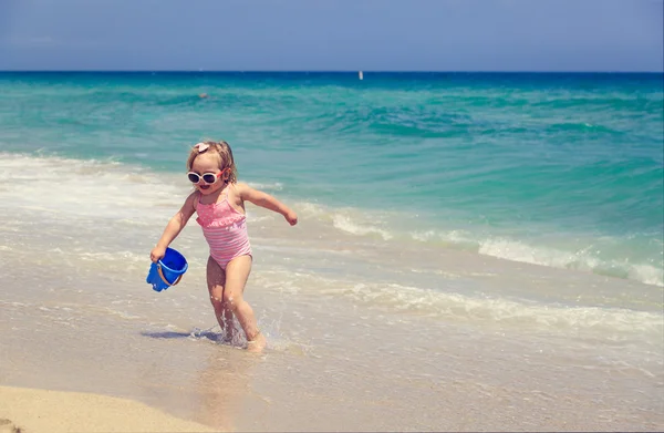 Schattig klein meisje spelen met water op het strand — Stockfoto