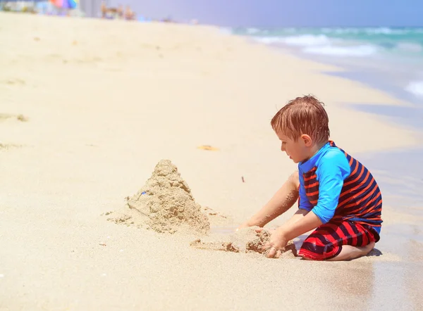 Mały chłopiec bawić się piaskiem na letniej plaży — Zdjęcie stockowe