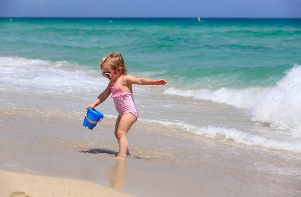 Schattig klein meisje spelen met water op het strand — Stockfoto