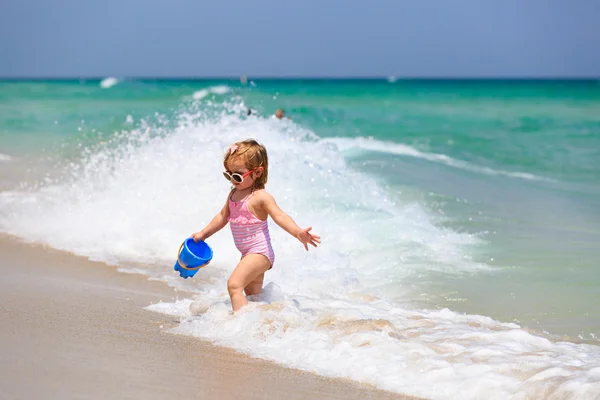 Roztomilá holčička hrát si s vodou na pláži — Stock fotografie