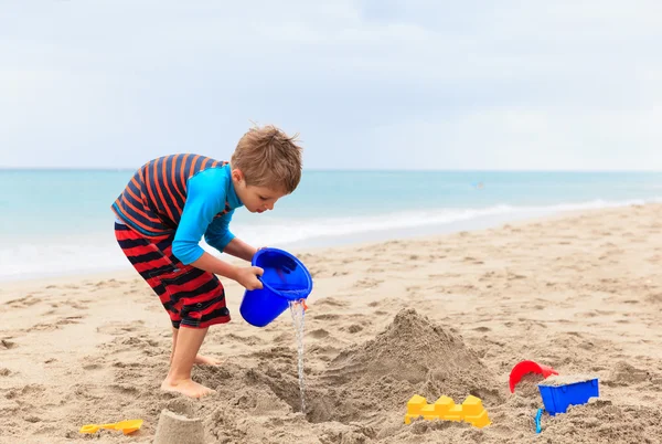 Malý chlapec hrát s pískem na letní pláži — Stock fotografie