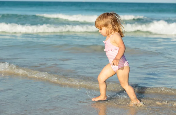 Schattig klein meisje spelen met water op het strand — Stockfoto