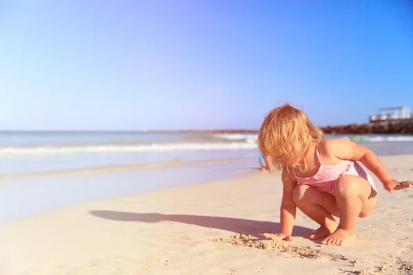 Klein meisje spelen met zand op het strand — Stockfoto