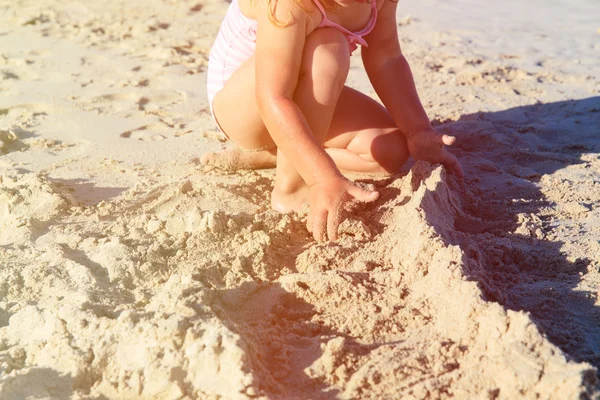 Niña jugando con arena en la playa — Foto de Stock