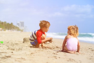Çocuklar yaz plajında kumla oynarlar.