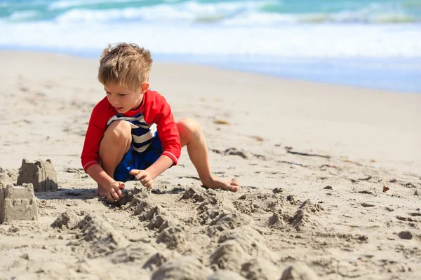 Маленький хлопчик грає з піском на літньому пляжі — стокове фото