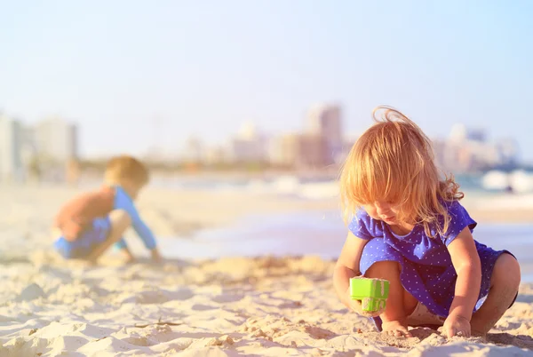 Little girl and boy play with sand on sunset beach — Stock Photo, Image