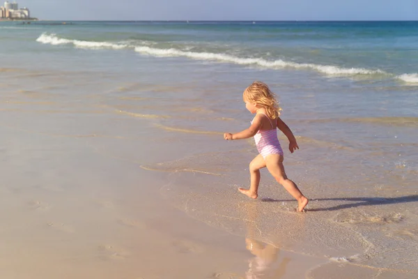 Petite fille courir jouer avec des vagues sur la plage — Photo