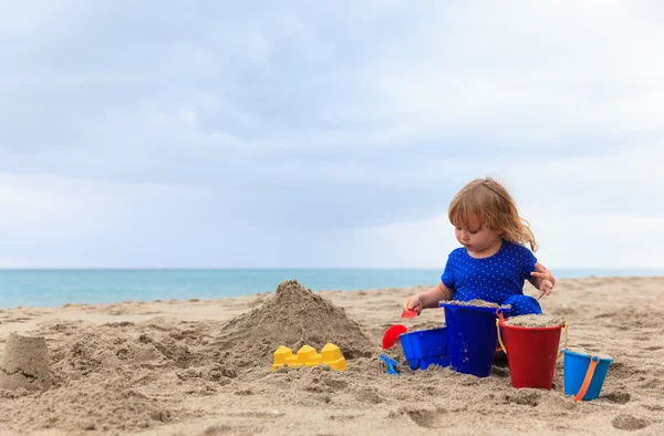 Kleines Mädchen spielt mit Sand am Strand — Stockfoto