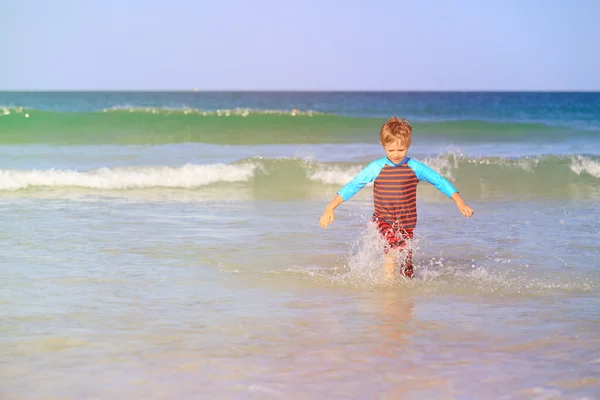Маленький мальчик бежит брызгает водой на пляже — стоковое фото