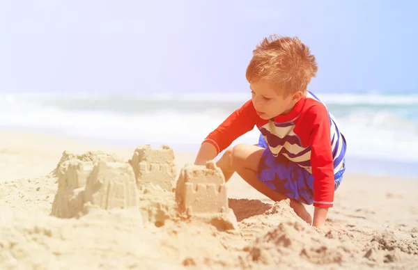 Küçük çocuk yaz kumsalında kumla oynuyor. — Stok fotoğraf