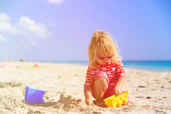 Маленькая девочка играет с игрушками на пляже — стоковое фото