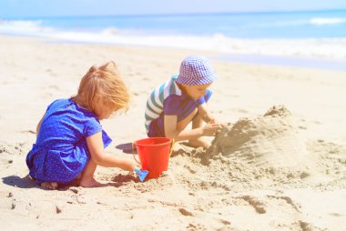 Çocuklar yaz plajında kumla oynarlar.