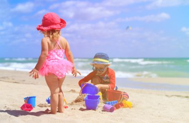 Çocuklar yaz plajında kumla oynarlar.