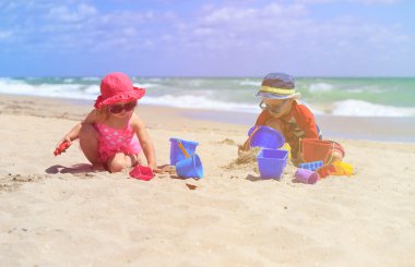 Çocuklar yaz plajında kumla oynarlar.