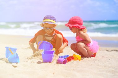 Çocuklar yaz plajında kumla oynarlar.