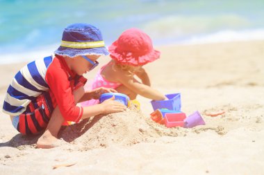 Çocuklar yaz plajında kumla oynarlar.