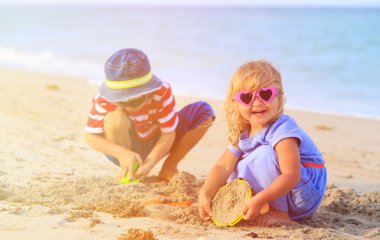 Çocuklar yaz plajında kumla oynarlar.