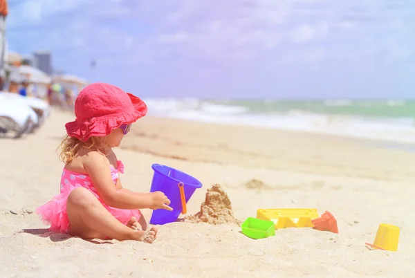 Little girl plays with sand on beach — Stock Photo, Image