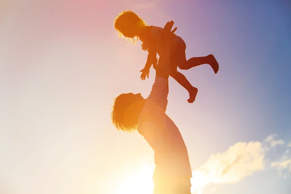 Édesapja és a kis lánya sziluettek a naplemente — Stock Fotó