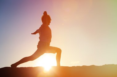 Gün batımında Yoga yapan genç erkek