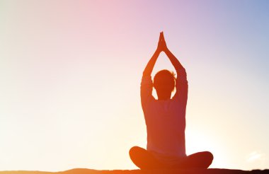 Gün batımında Yoga yapan genç erkek