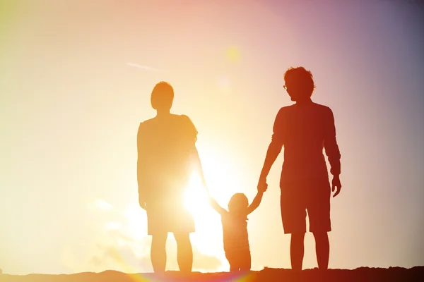 Família feliz com criança juntos ao pôr do sol — Fotografia de Stock