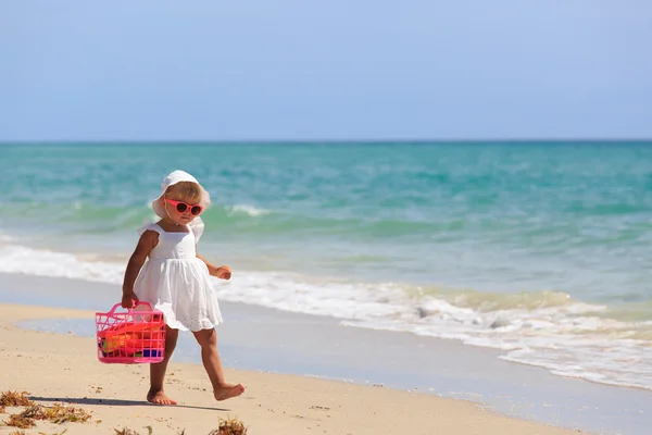 Девушка ходит с игрушками на песчаном пляже — стоковое фото