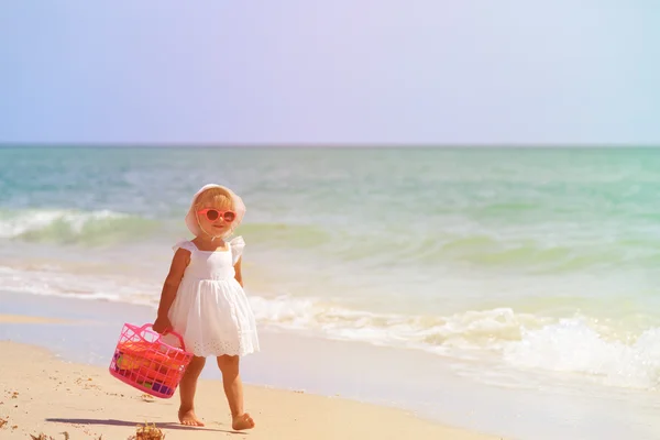 Meisje loopt met speelgoed aan zandstrand — Stockfoto