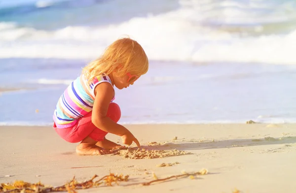 Meisje speelt met zand op strand — Stockfoto