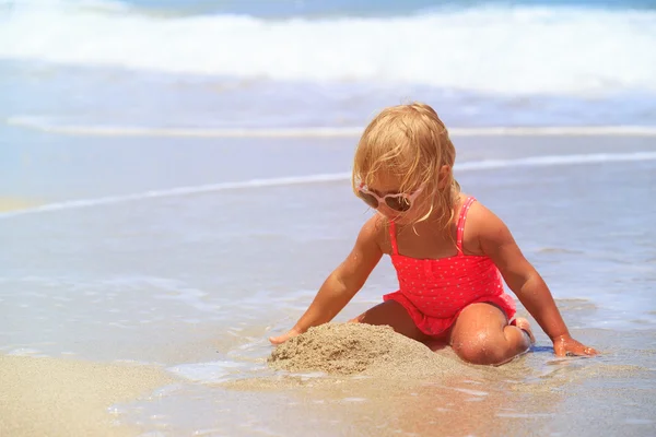 Meisje speelt met zand op strand — Stockfoto