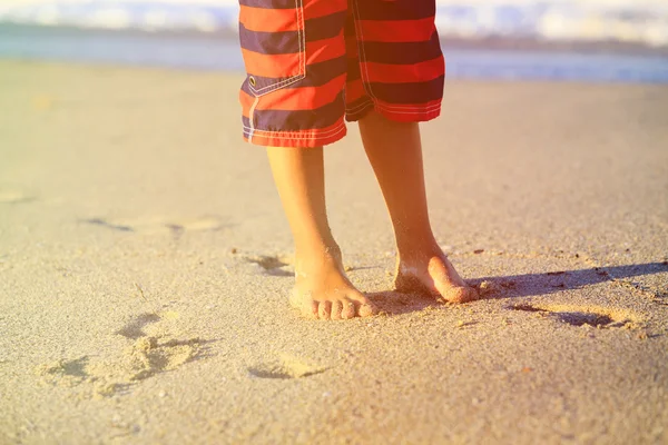 Los pies de un niño en la playa de arena — Foto de Stock