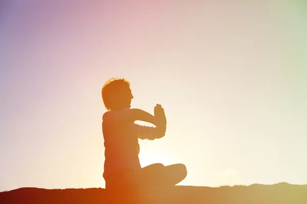 Jeune homme faisant du yoga au coucher du soleil — Photo